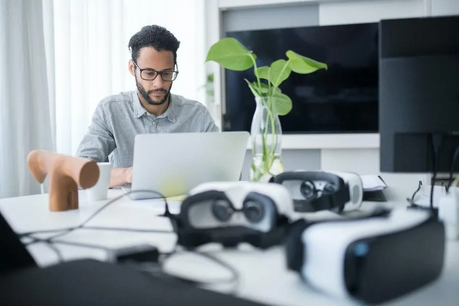 Someone working at a desk with VR headsets surrounding them